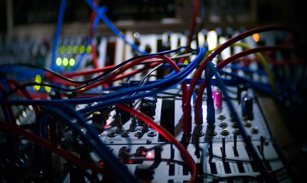 A close up of wires plugged into a sound board.